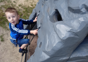 Chłopiec wspina się na skałkę wspinaczkową